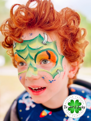 Smiling face with a custom face paint design: dragon mask.