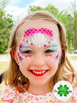 Smiling face with a custom face paint design: mermaid mask.