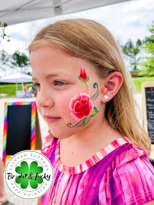 Smiling face with a custom face paint design: rose cheek.