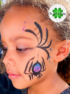 Smiling face with a custom face paint design: spider cheek.