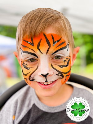 Smiling face with a custom face paint design: tiger face.